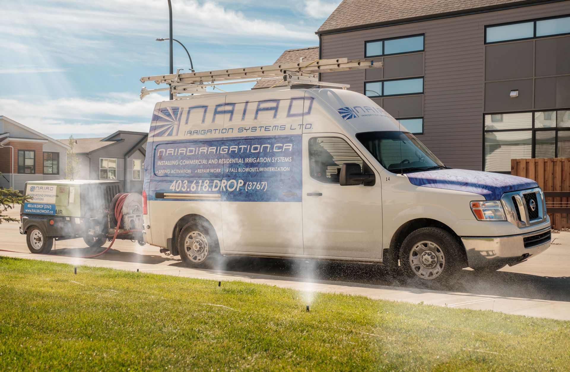 Water is expelled from a sprinkler system for winterization. A Naiad service van stands by to haul the air compressor in the background.